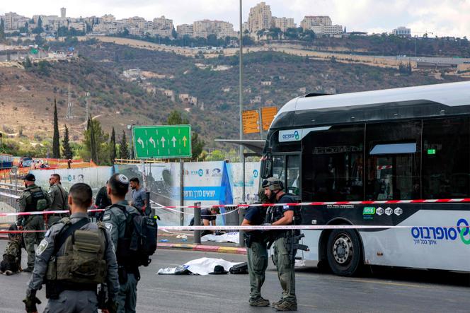  Israeli security forces gather by a body next to a bus at the scene of a shooting at the Ramot road junction in Israeli-annexed east Jerusalem on September 8, 2025.
