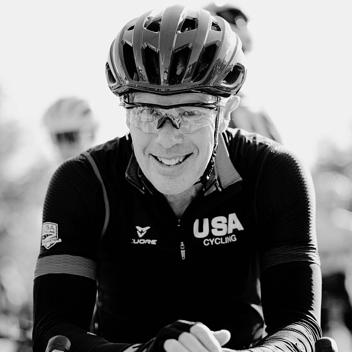 Greg Allen posing for a picture while wearing a USA cycling jacket