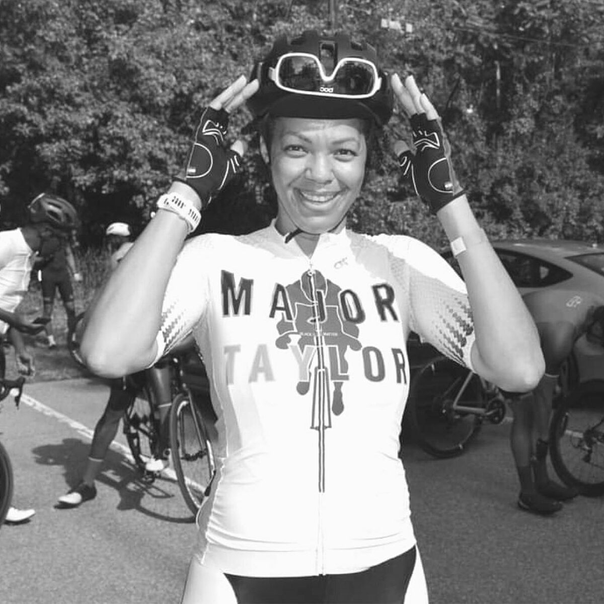 Dereka Hendon posing for a photo while putting her sunglasses on her helmet