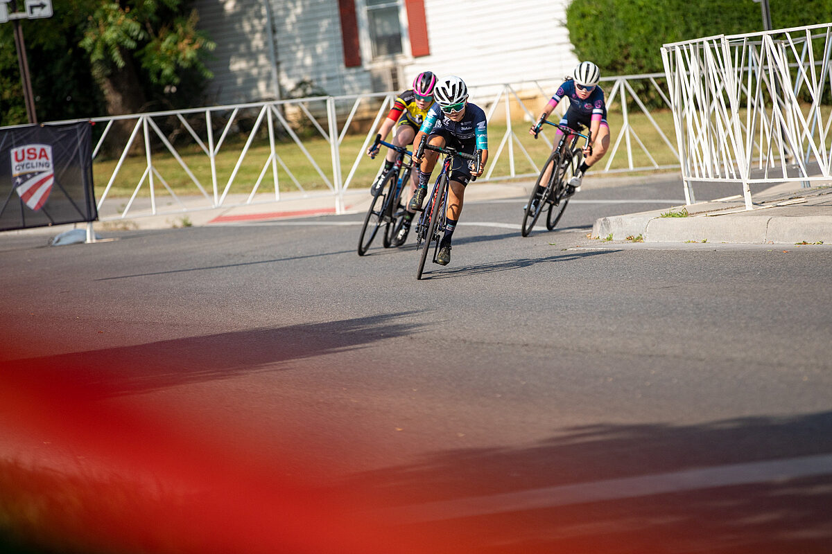 Three junior bike racers going around a corner in a criterium race