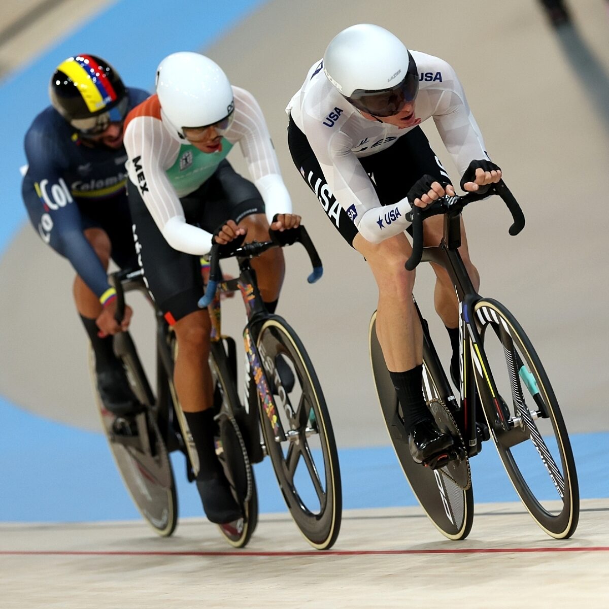 Track cyclists racing in velodrome.