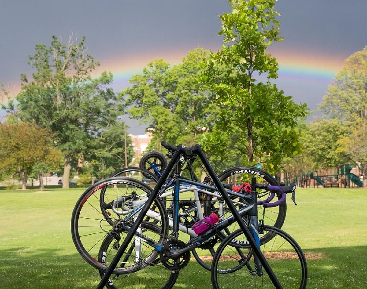 Road bikes hanging on a bike stand with a bright rainbow in the distance.