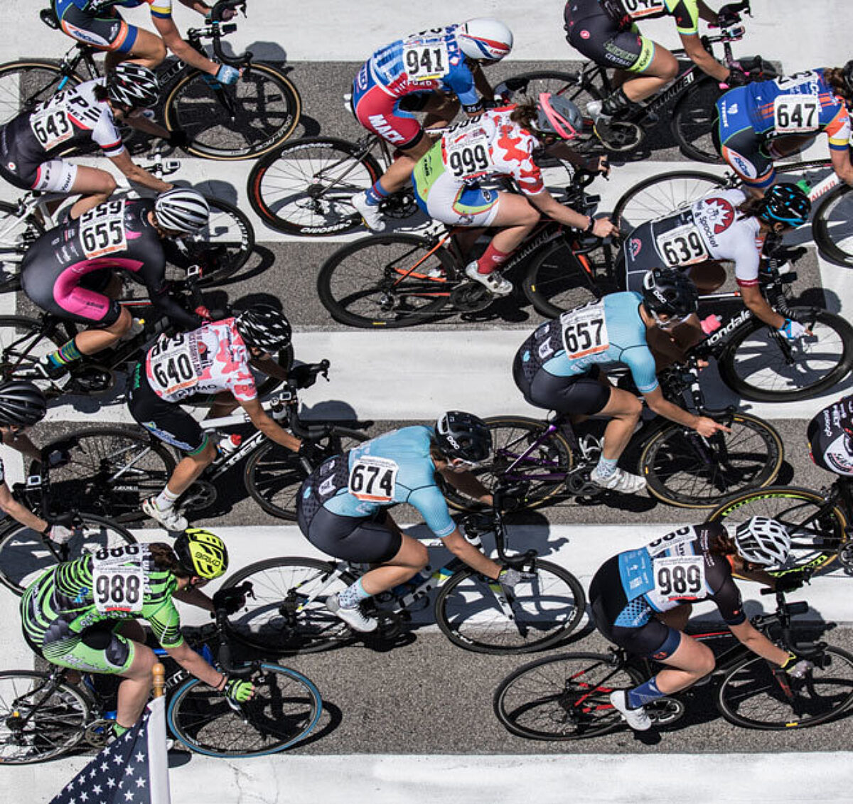 Road race shot from directly above, looking down at cyclists going over a crosswalk.