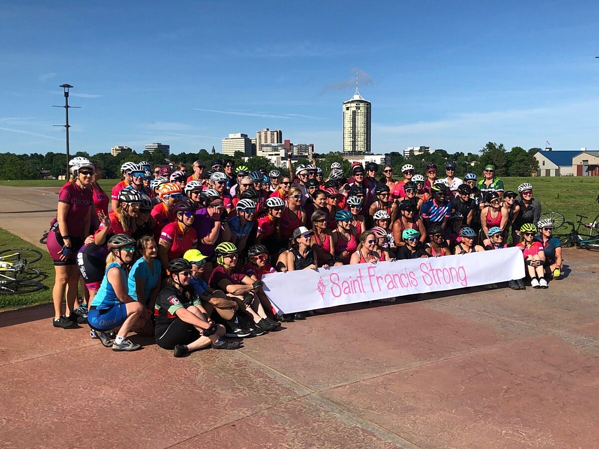 A bike club posing and holding up a sign for a photo.
