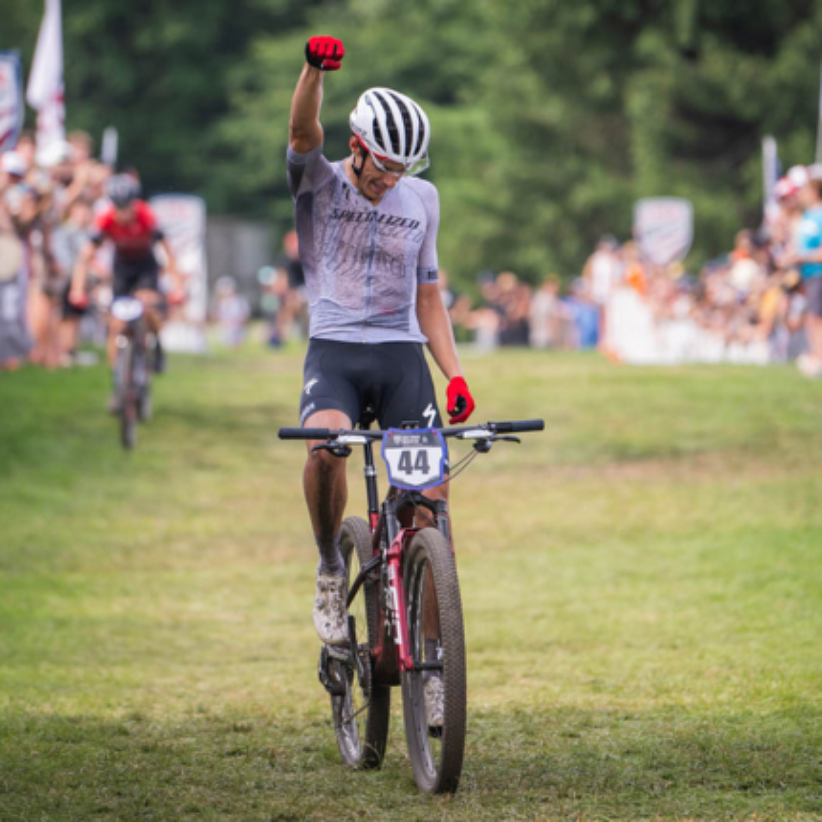 Mountain bike racer celebrating while riding his bike over the finish line